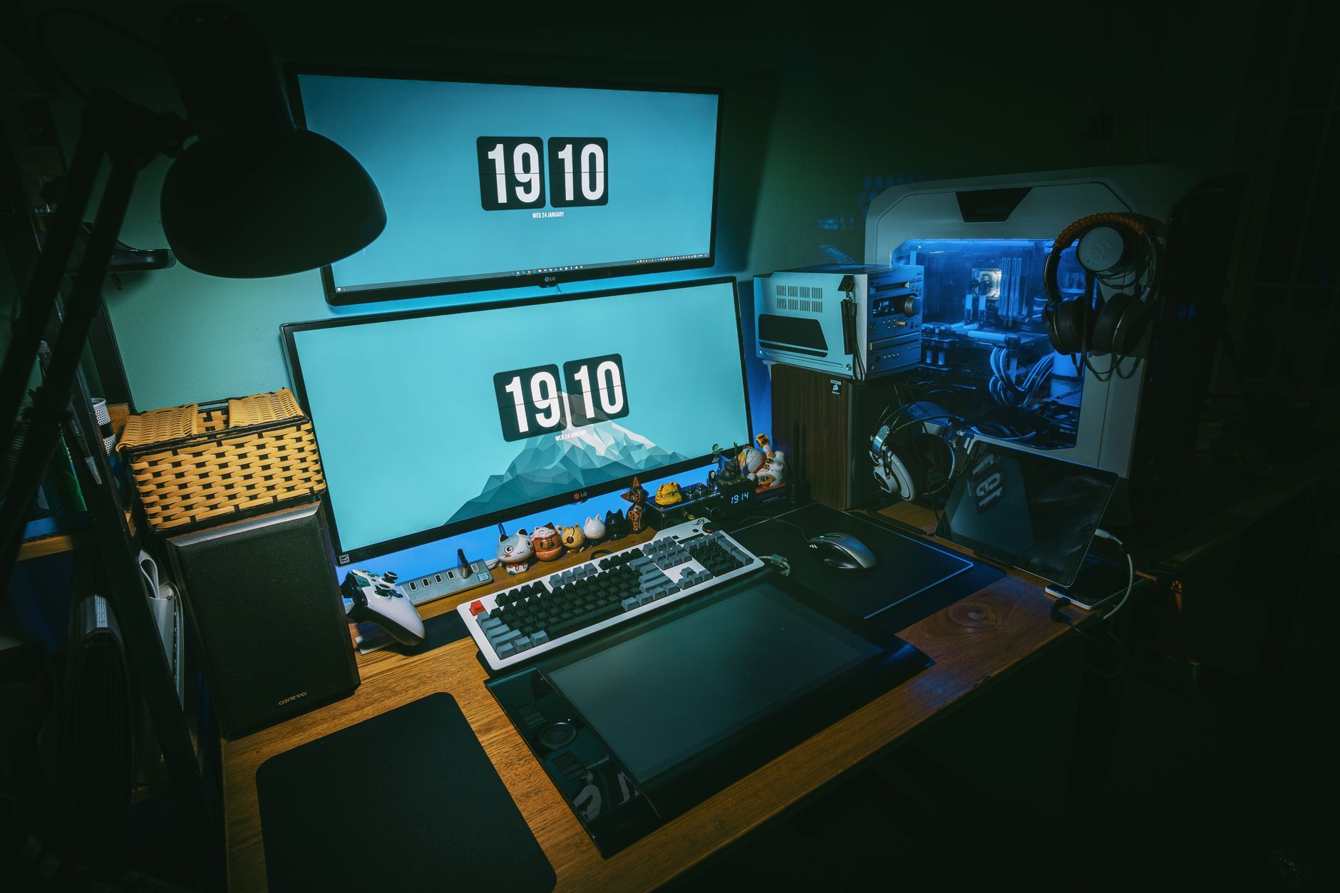 Bureau de jeu informatique avec deux écrans, un clavier mécanique, une manette et une tour de PC.